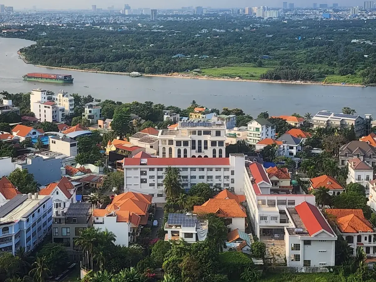 A riverside neighbourhood with red roofs and trees, seen from above